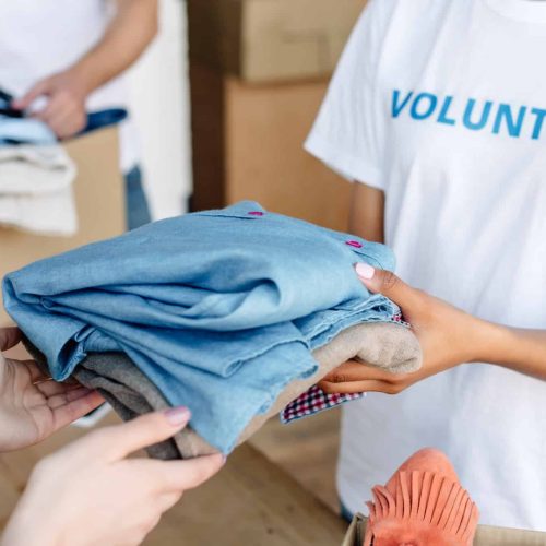 cropped-view-of-volunteer-giving-clothes-to-woman-in-charity-center.jpg